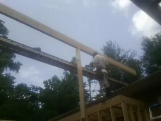 Carpenter setting a ridge beam over a new addition frame — Ice Dam Removal by Roofing Brothers in Altavista