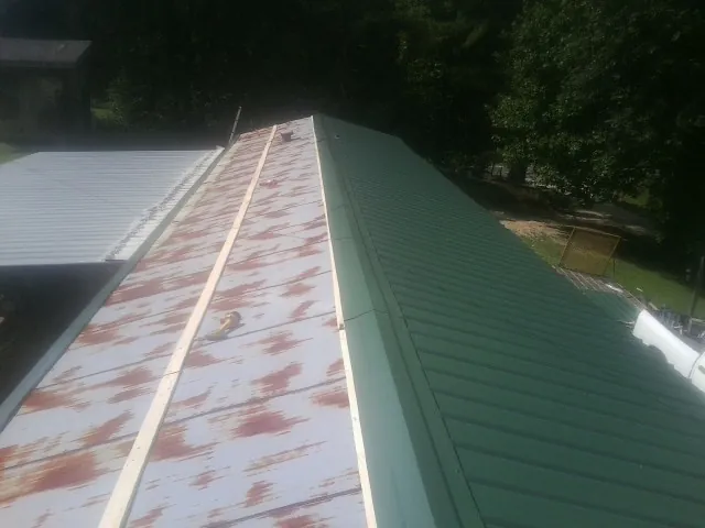 Old rusted panels beside newly installed green metal roofing — Wind Damage Roof Repair by Roofing Brothers in Altavista