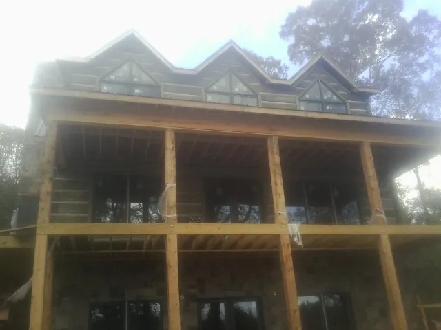 Dormers and porch framing on a large log home under construction — Roof Coating work by our crew in Altavista