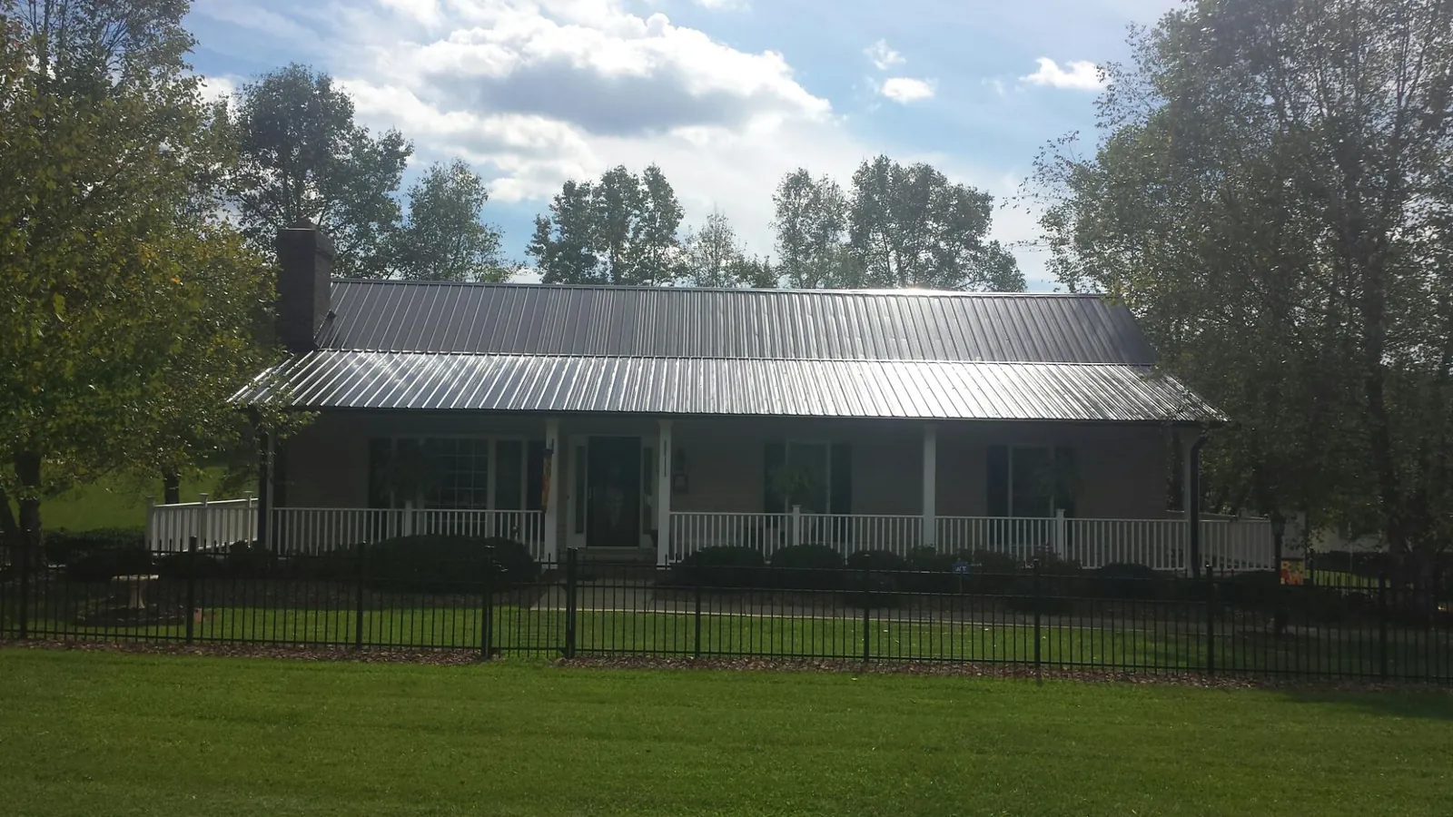 Gray metal roof on a brick ranch with a full width front porch — Gutter Guard Installation work by our crew in Altavista