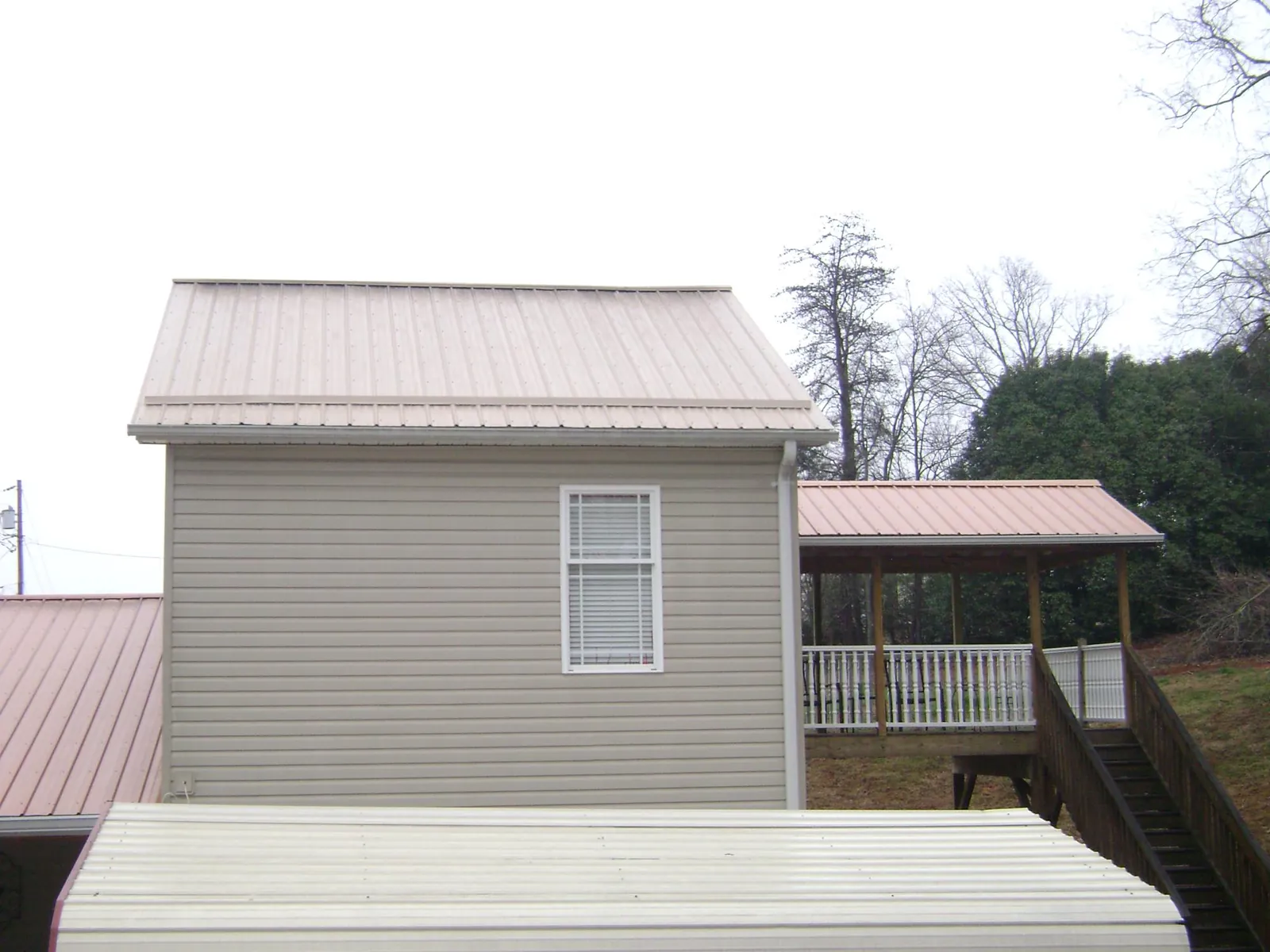 Tan metal roofs on a two story addition and attached porch, from a Roof Replacement job in Altavista