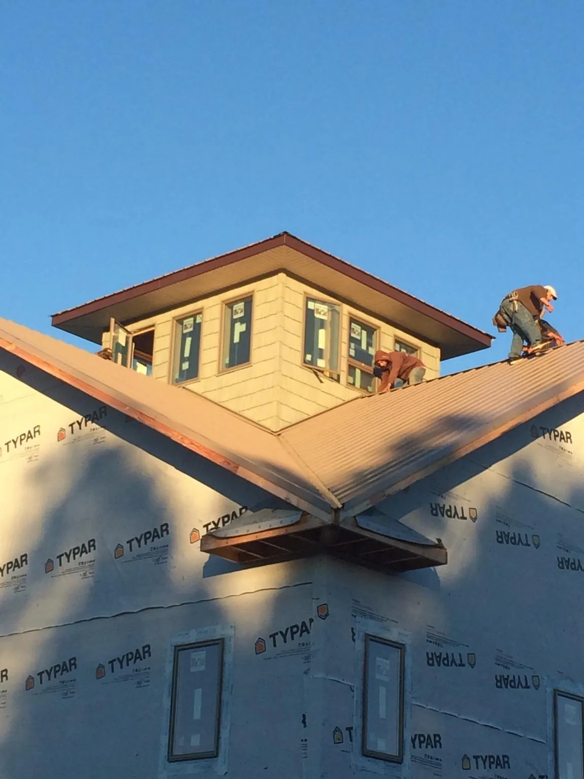 Roofers working around a rooftop cupola on a new metal roof at sunset — Roof Waterproofing in Altavista by Roofing Brothers